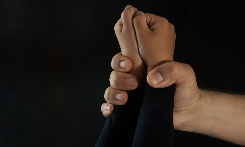 Child's hand restrained by an adult predator