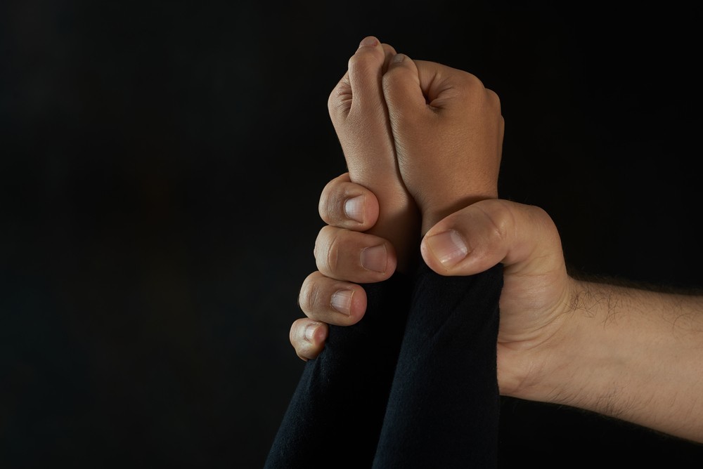 Child's hand restrained by an adult predator