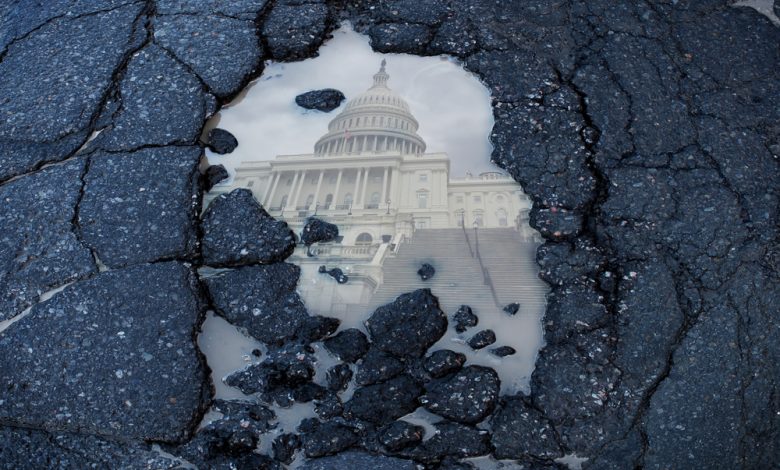 a puddle in the street reflects the Capitol building