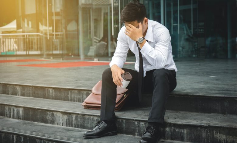 Image of unemployed businessman sitting on stairs.