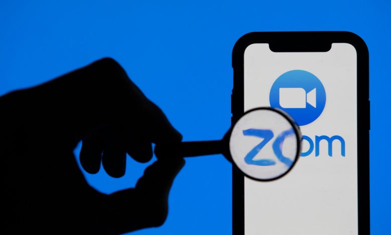 Image of phone using Zoom conference app with magnifying glass.