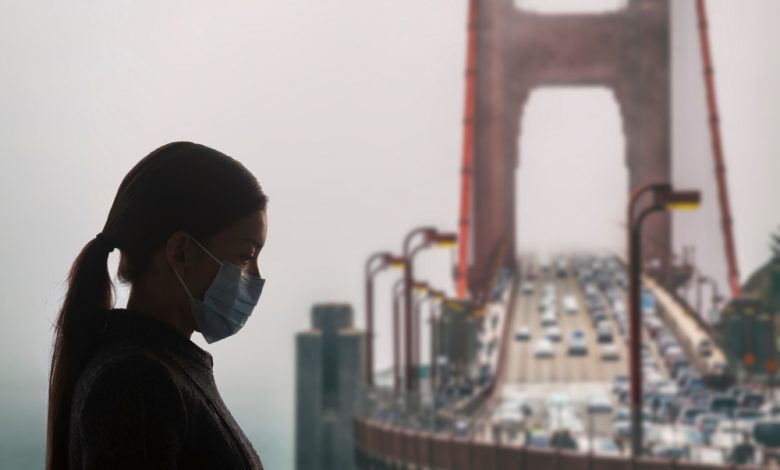 Image of women wearing surgical mask next to the Golden Gate bridge