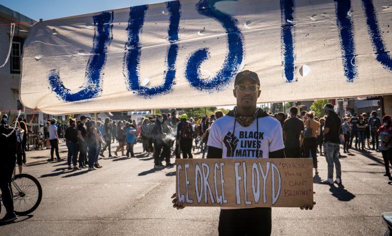 Man holding a sign reading “Justice for George Floyd”.