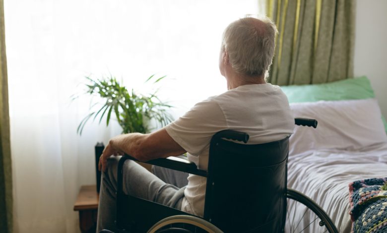 Senior man in nursing home looking outside a window.