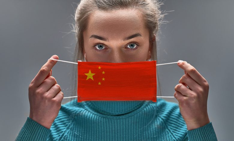 Image of women putting on face mask with the design of a China's flag.