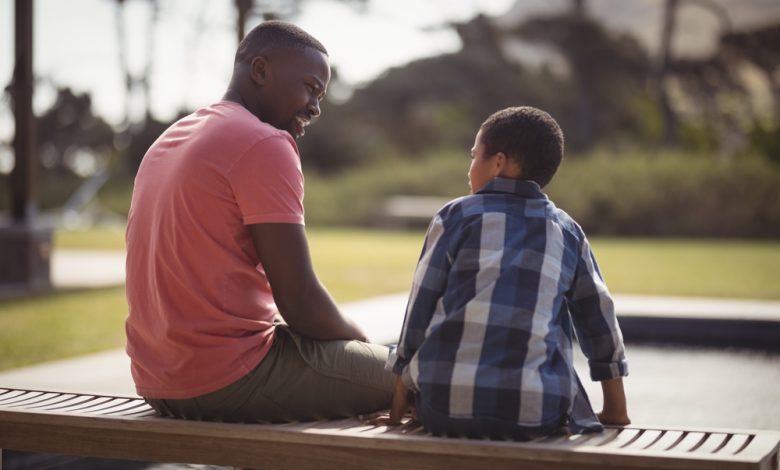 Father and son talking at park.