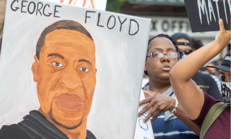 Protesters holding a poster with a drawing of George Floyd.