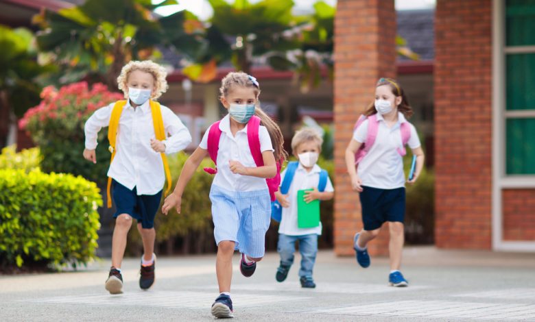 School child wearing face mask during corona virus and flu outbreak. Boy and girl going back to school after covid-19 quarantine and lockdown.