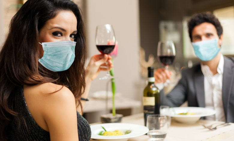 Couple toasting wineglasses in a luxury restaurant and wearing masks.