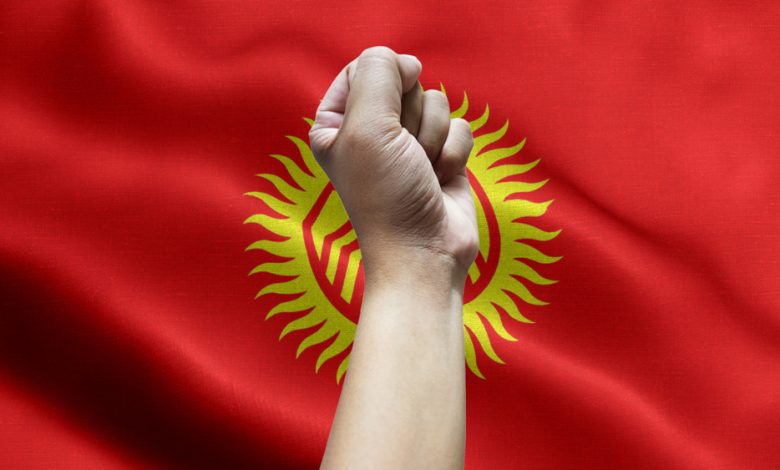 Fist in the air with the flag of Kyrgyzstan on the background