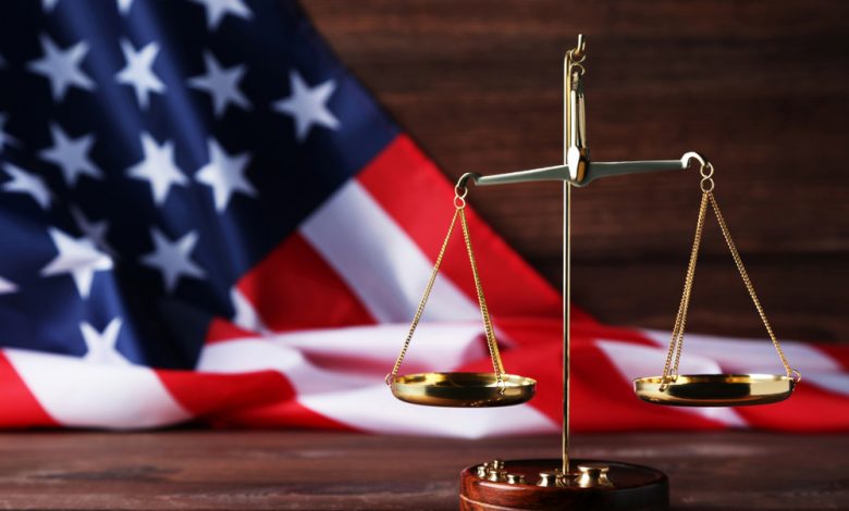 Scales of justice with american flag on brown wooden table.