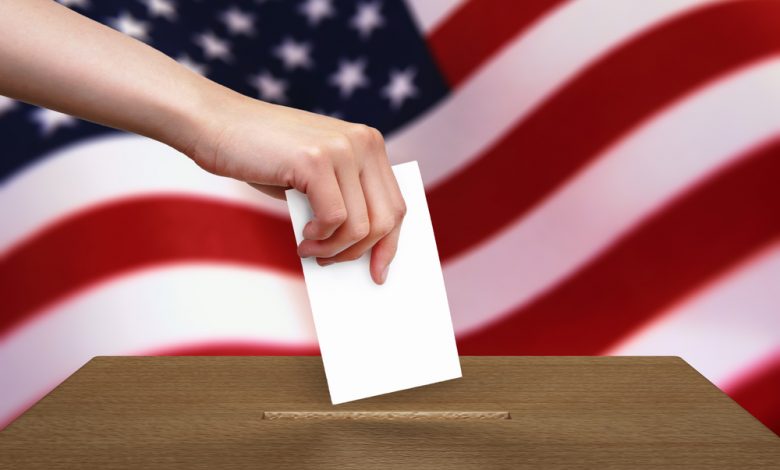 Hand with ballot and wooden box with American Flag of USA