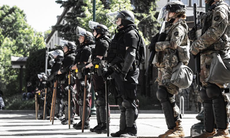 Police officers and National Guard stand in riot gear in South Minneapolis.