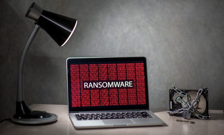 Computer screen with ransomware attack alert in red digital binary background with hard disk drive lock.