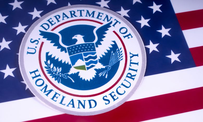 Symbol of the US Department of Homeland Security pictured over the US Flag.