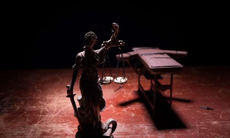 Lethal injection concept image showing injection bed and a statue of lady justice.