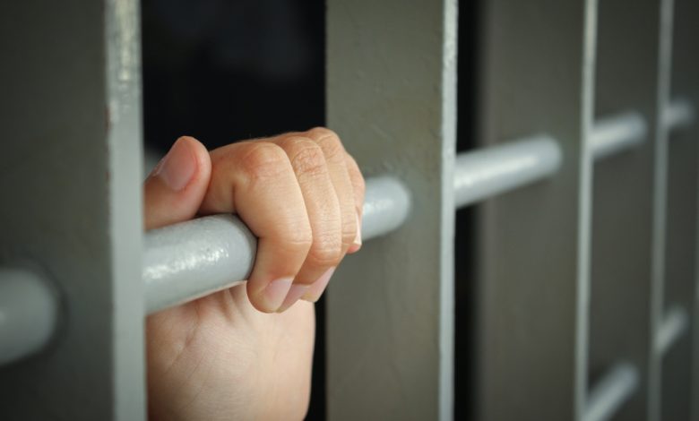 Female inmate holding prison bars.