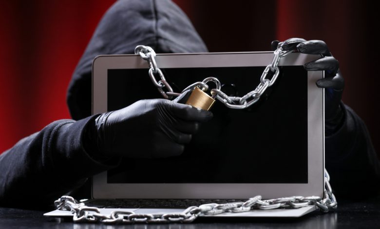 Hacker in black pullover and black mask trying to hack.