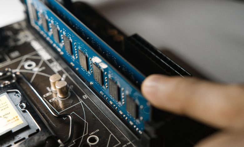 Person installing a RAM module on a computer motherboard.