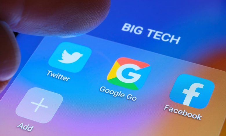 Google, Facebook, Twitter apps seen on a smartphone screen and blurred finger pointing at them.