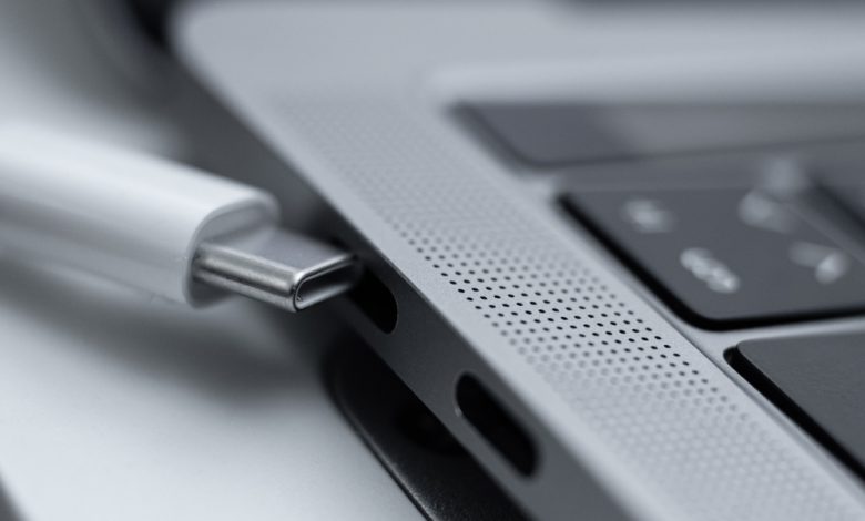 White charging cable next to a MacBook Pro.