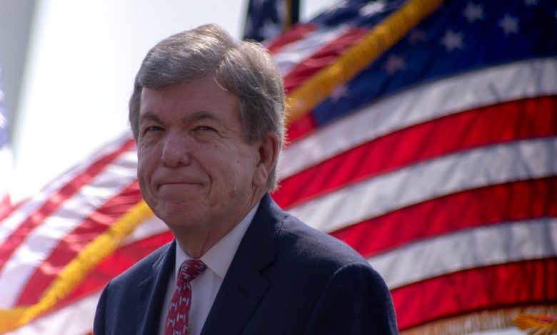 Senator Roy Blunt sits in front of American flags.