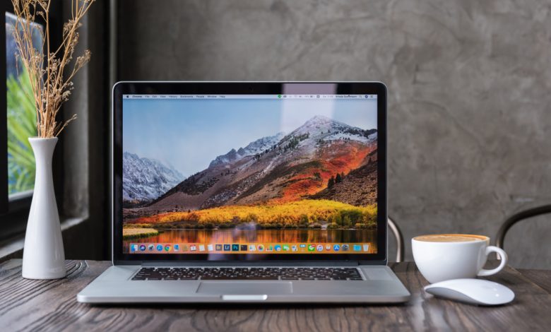 SONGKHLA, THAILAND - July 7, 2018: Apple Macbook pro computer with dried flower vase and latte art coffee on wooden table, created by Apple Inc.