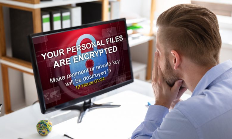 Worried Businessman Looking At Computer With Ransomware Word On The Screen At The Workplace