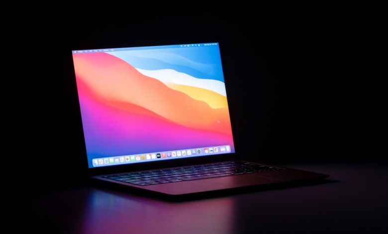 Portland, OR, USA - Feb 22, 2021: The new MacBook Air with Apple's M1 chip and the latest macOS Big Sur isolated on a desk in the dark.