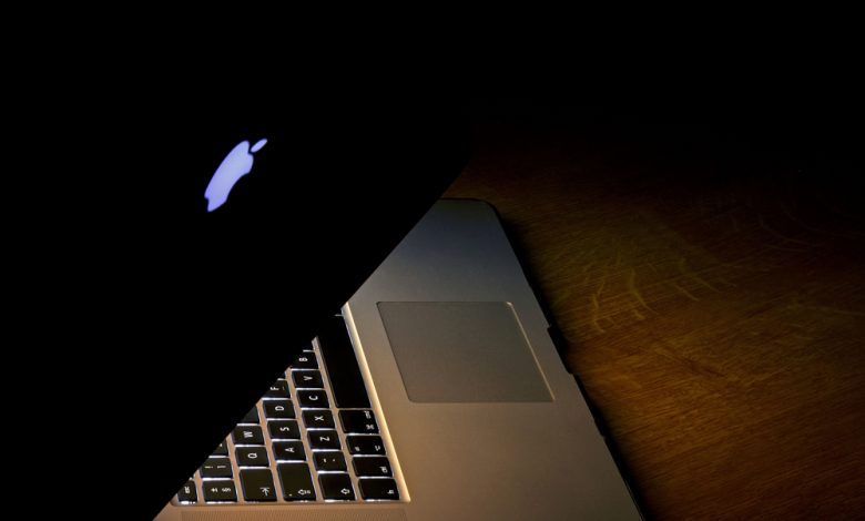 Warsaw,Poland-February 2016: Shot of activated MacBook Pro 15 Retina standing on wooden table in darknes.Editorial.Horizontal view from side