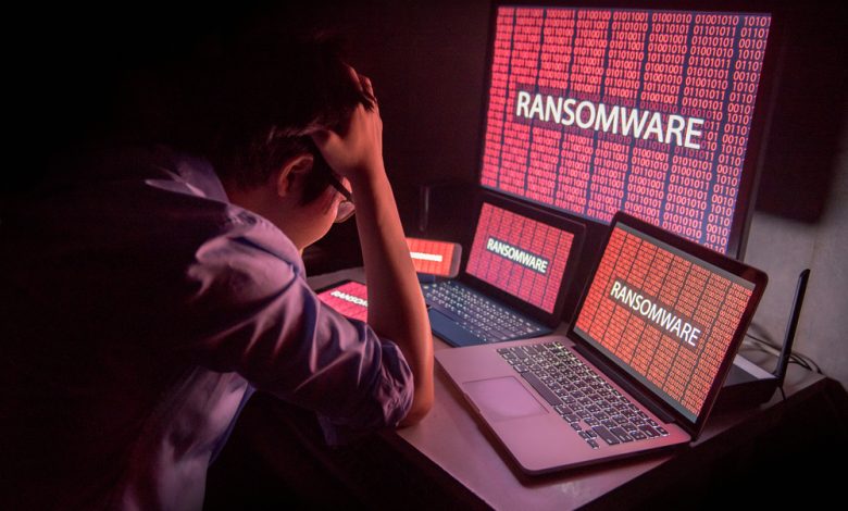 Young Asian male frustrated, confused and headache by ransomware attack on desktop screen, notebook and smartphone, cyber attack and internet security concepts