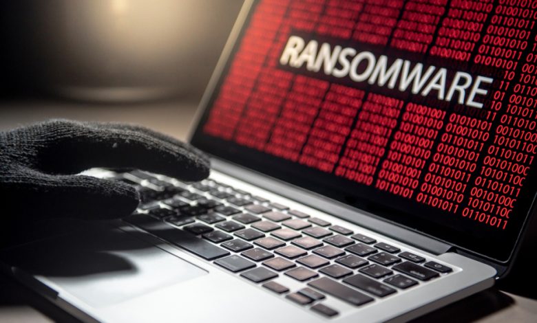 Male hacker hand on laptop computer keyboard with red binary screen of ransomware attacking. Cyber attack and Internet data security concept