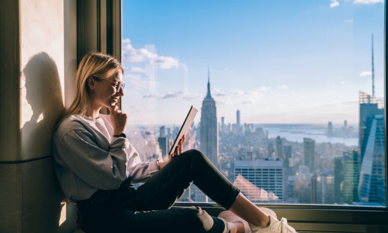 Woman looking at tablet thoughtfully with manhattan skyline in the background.