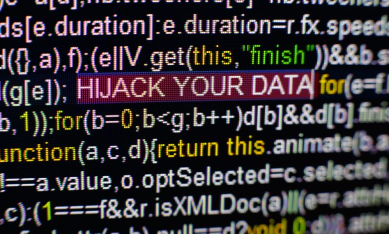 Macro photo of computer screen with program source code and highlighted HIJACK YOUR DATA inscription in the middle.