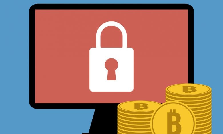 Computer encrypted by ransomware with Bitcoins in front of it.