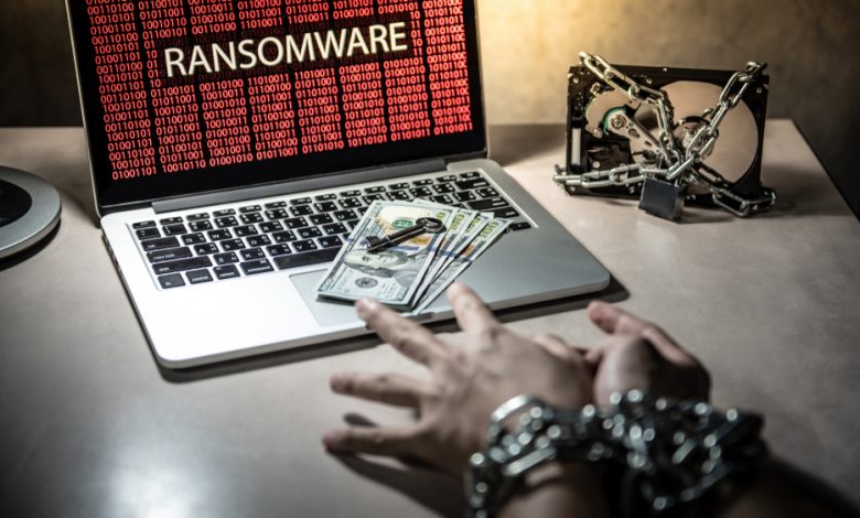 Cyber attack and Internet security concept: Hands tied up by chain and lock trying to grab dollar banknote and key on keyboard, Hard disk file locked with laptop computer show ransomware attacking.