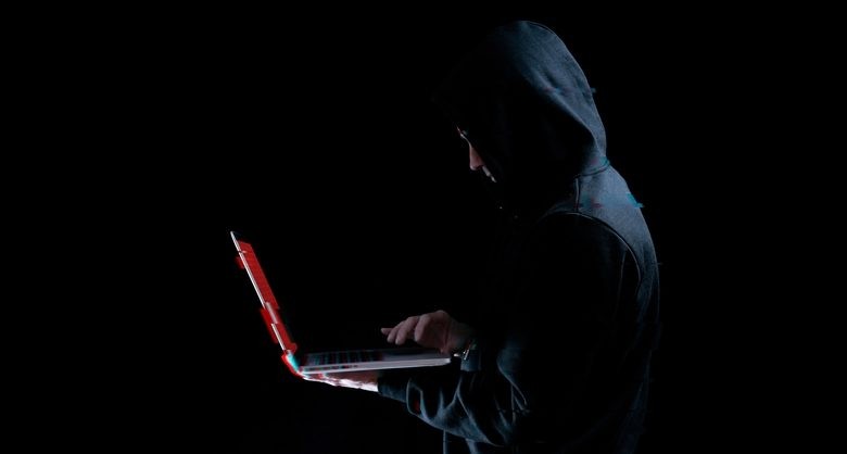 Hacker attack cyber security. Digital laptop in hacker man hand isolated on black.