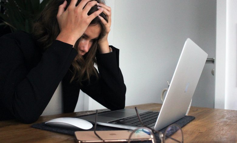 woman in black long sleeve shirt covering her face with her hands