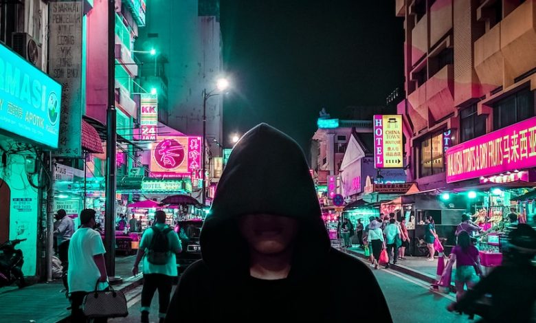 man in black hoodie walking on street during night time