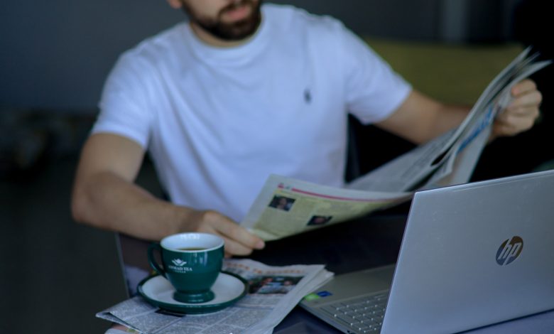 a man sitting at a table reading a newspaper