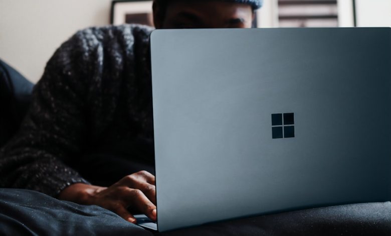 person in gray knit cap using microsoft surface computer in cobalt blue colour